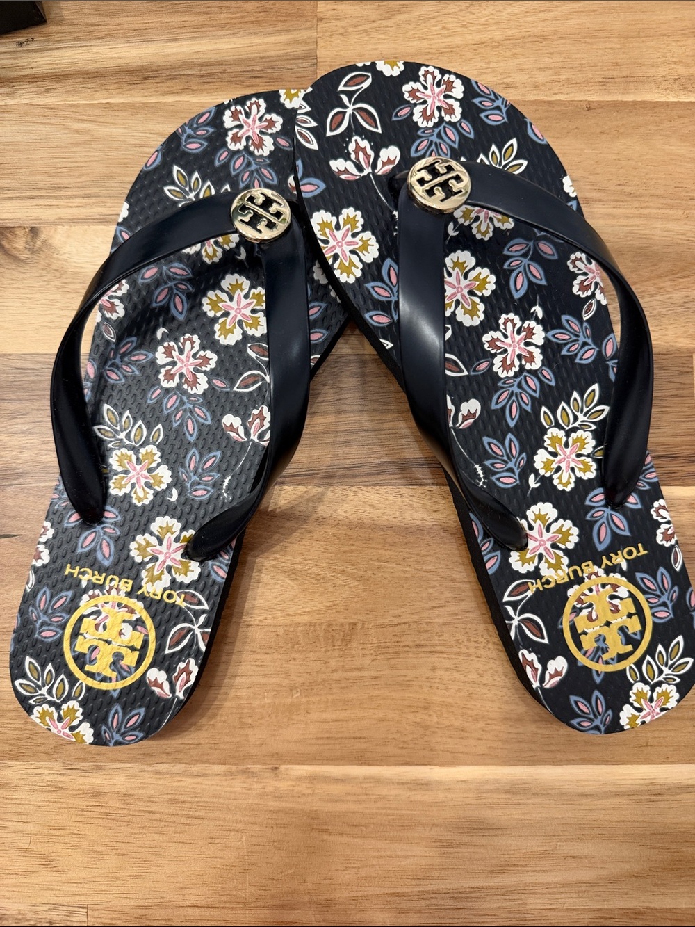 Tory Burch Black Floral Logo Flip Flops with Gold Emblems